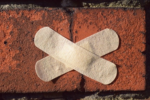 Pansements collés en croix sur la fissure d'un mur en brique